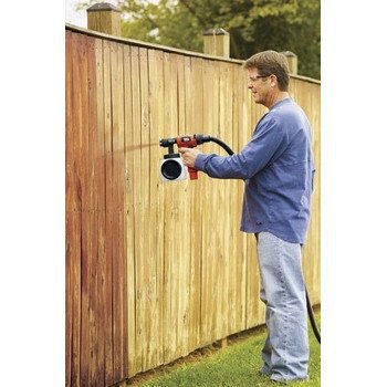 Man using an HVLP paint sprayer on a fence